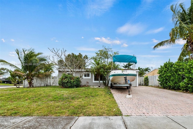 view of front facade with a front yard, decorative driveway, fence, and stucco siding