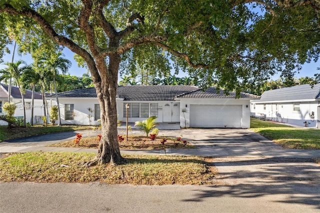 ranch-style house featuring a garage, driveway, a tiled roof, and stucco siding