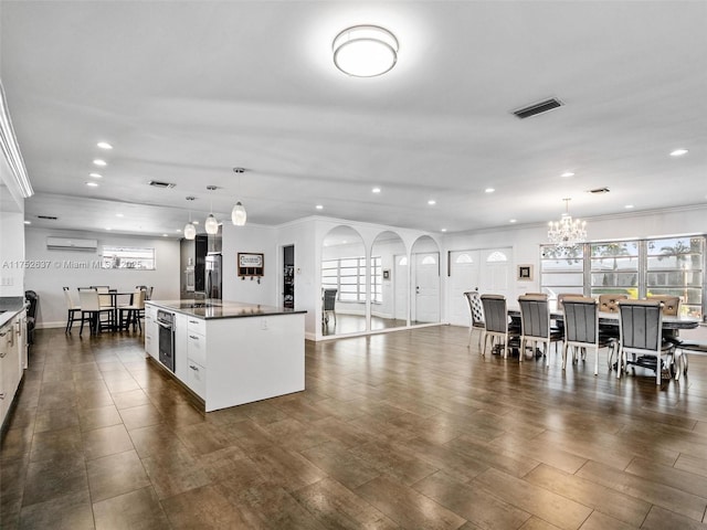 kitchen featuring a wall unit AC, oven, visible vents, an island with sink, and crown molding