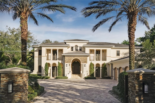 view of front of house featuring a balcony, decorative driveway, and stucco siding