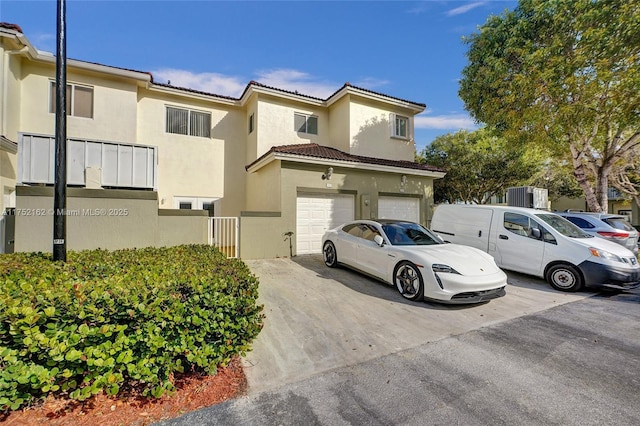 view of front of house featuring driveway, an attached garage, a tile roof, and stucco siding