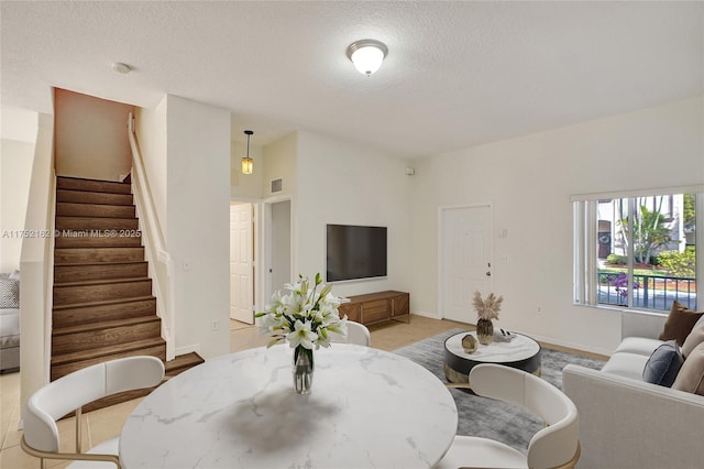 living room with stairs, a textured ceiling, and baseboards