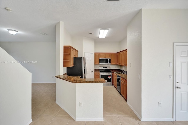 kitchen with light tile patterned floors, stainless steel appliances, open shelves, brown cabinetry, and dark stone counters