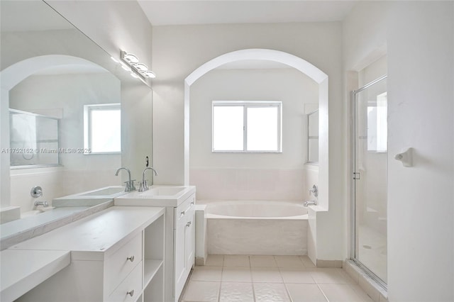 bathroom featuring a garden tub, two vanities, plenty of natural light, and a sink