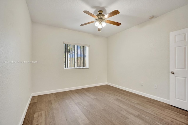 empty room featuring a ceiling fan, baseboards, and wood finished floors