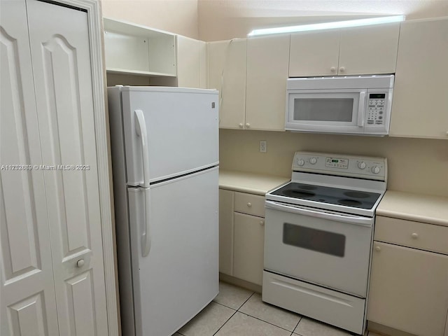 kitchen with white appliances, light tile patterned floors, white cabinetry, and light countertops