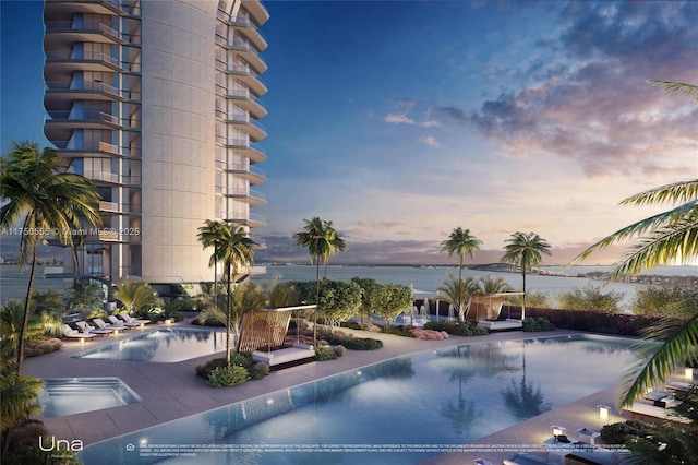 pool at dusk featuring a water view and a community pool