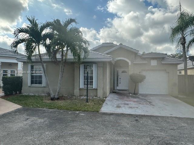 view of front facade with a garage, concrete driveway, and stucco siding