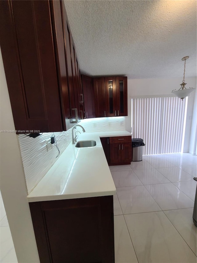 kitchen featuring a textured ceiling, light countertops, and a sink