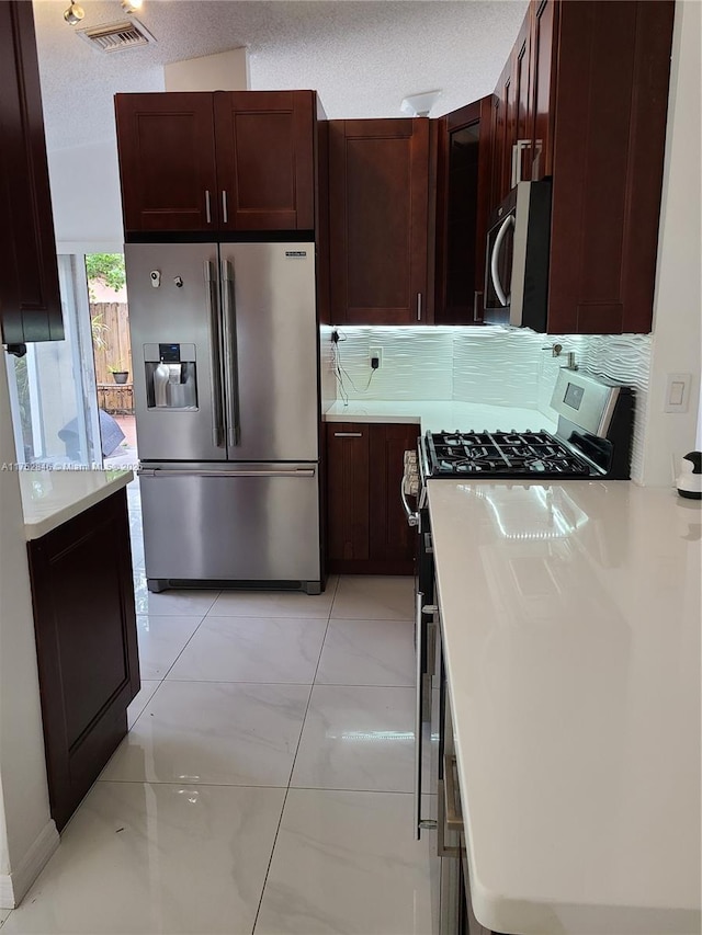 kitchen with tasteful backsplash, visible vents, stainless steel appliances, a textured ceiling, and light countertops