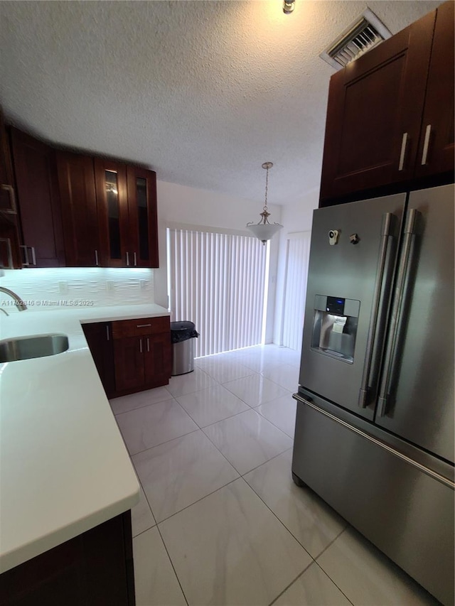 kitchen with visible vents, light countertops, a sink, and stainless steel fridge with ice dispenser