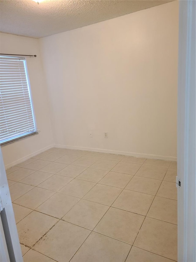 empty room featuring a textured ceiling and baseboards