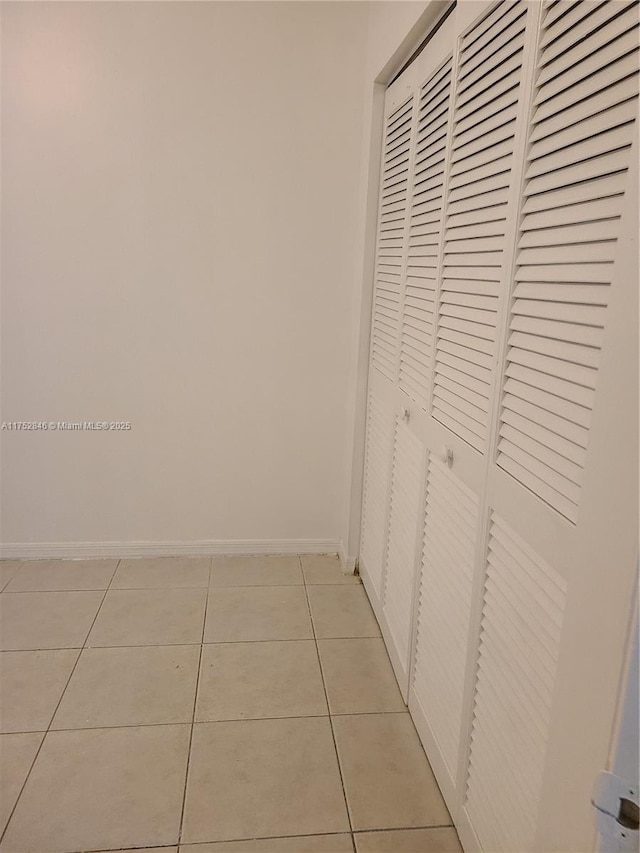 corridor featuring light tile patterned floors and baseboards