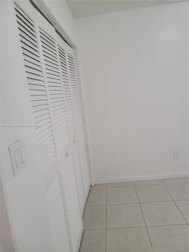 hall with light tile patterned flooring and baseboards