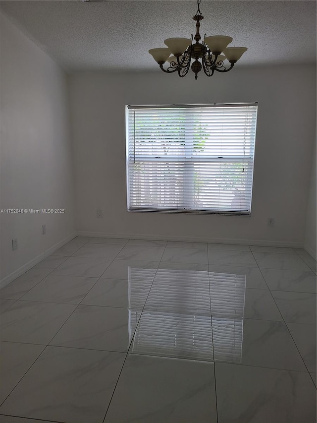 empty room with marble finish floor, a healthy amount of sunlight, and a textured ceiling