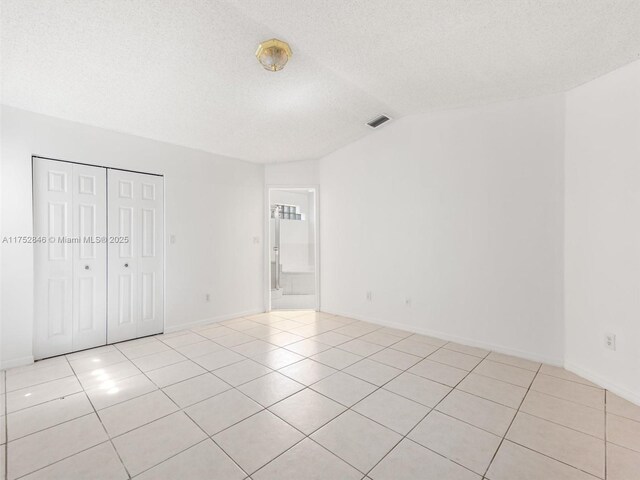 12344 SW 144th Ter, Miami, FL 33186 - unfurnished bedroom featuring light tile patterned floors, vaulted ceiling, baseboards, a closet, and a textured ceiling