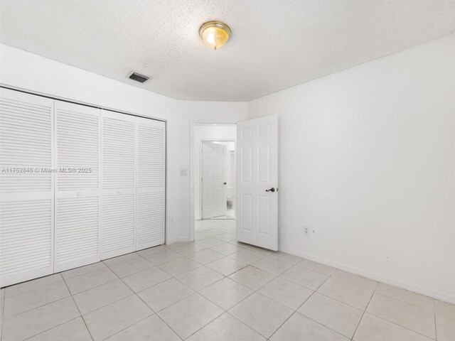 12344 SW 144th Ter, Miami, FL 33186 - unfurnished bedroom featuring a textured ceiling, light tile patterned floors, a closet, and baseboards