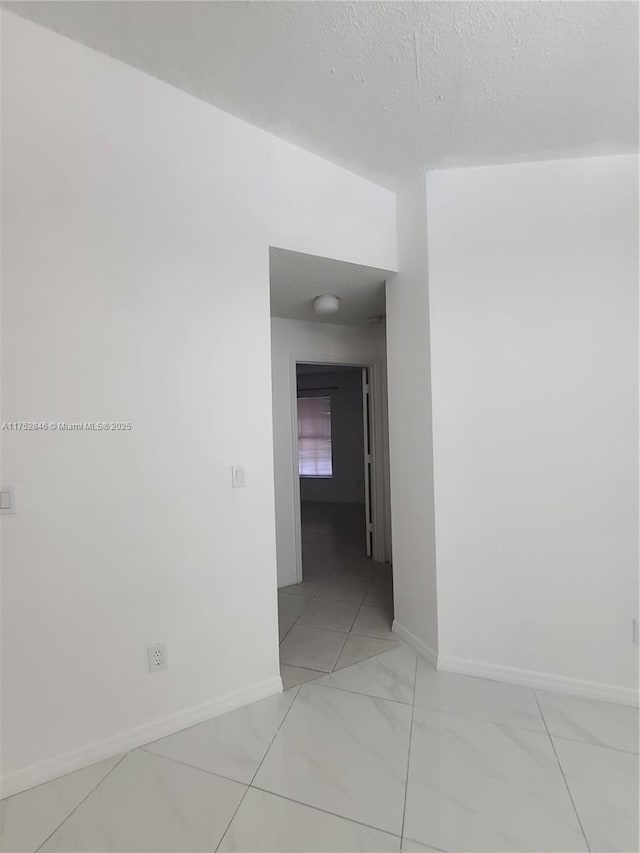 spare room featuring baseboards and a textured ceiling