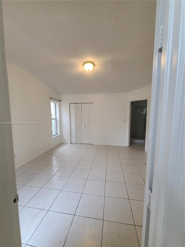 spare room with light tile patterned flooring and a textured ceiling