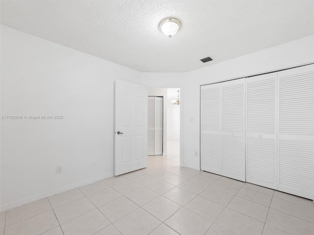 12344 SW 144th Ter, Miami, FL 33186 - unfurnished bedroom with light tile patterned floors, a closet, a textured ceiling, and baseboards