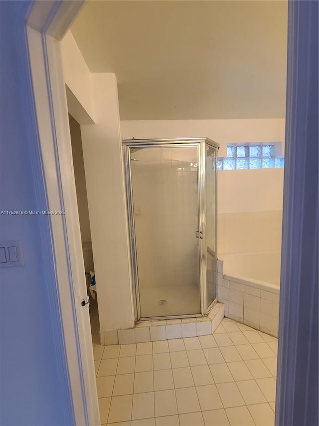 bathroom with a garden tub, a shower stall, and tile patterned floors