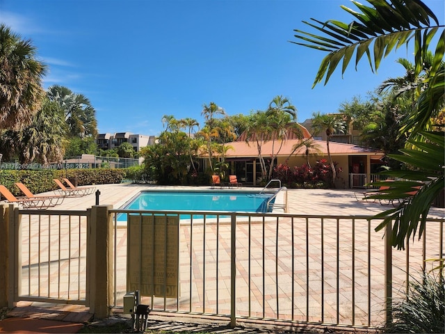 community pool with fence and a patio