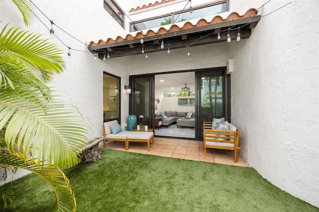 exterior space with a tile roof, stucco siding, outdoor lounge area, a lawn, and a patio area