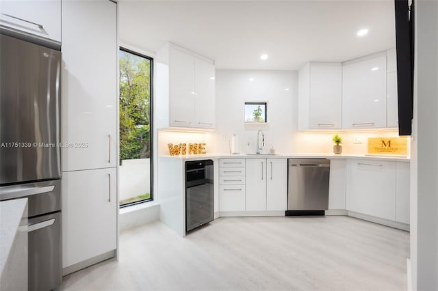 kitchen with white cabinets, modern cabinets, stainless steel appliances, light countertops, and a sink