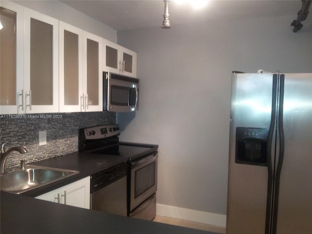 1470 NE 123rd St Unit A204, North Miami, FL 33161 - kitchen with stainless steel appliances, a sink, dark countertops, backsplash, and white cabinets
