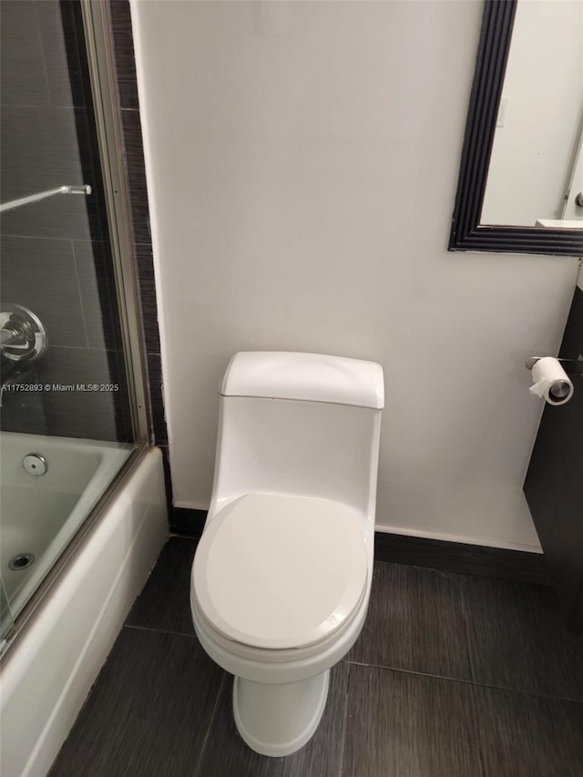 1470 NE 123rd St Unit A204, North Miami, FL 33161 - bathroom featuring toilet, baseboards, shower / bath combination with glass door, and tile patterned floors