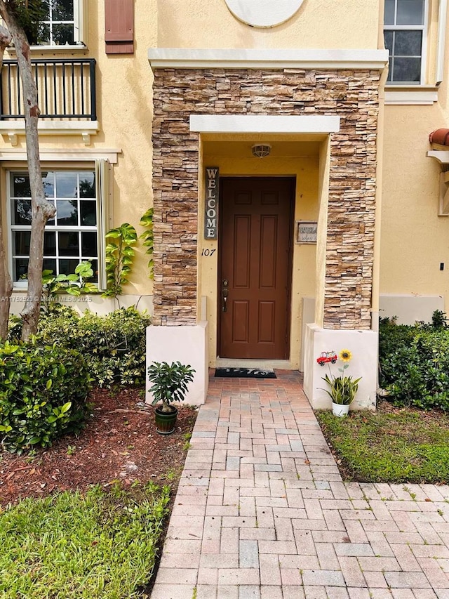 entrance to property featuring stone siding and stucco siding