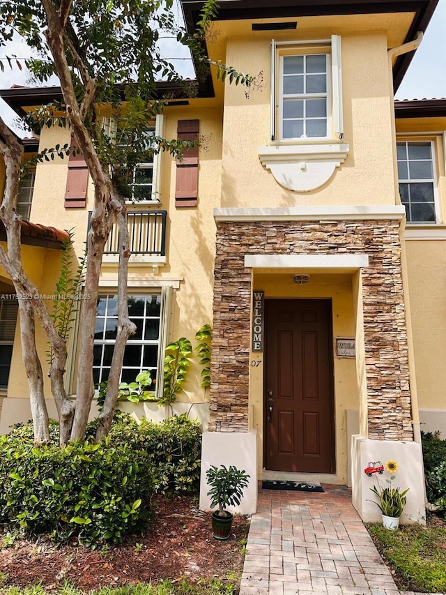 doorway to property featuring stone siding and stucco siding