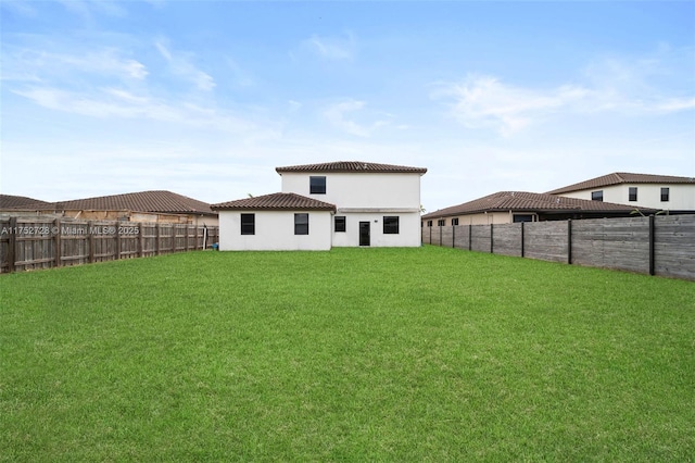 back of house with a yard, a fenced backyard, and stucco siding