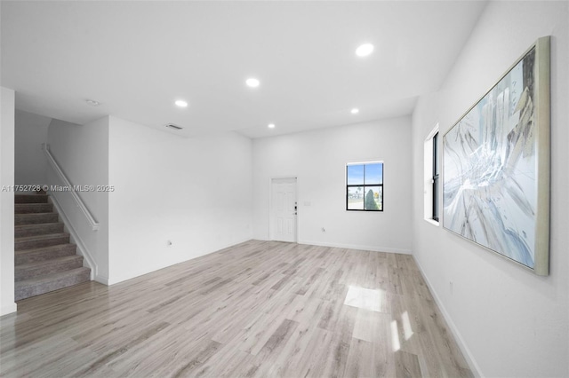 spare room featuring light wood-style floors, recessed lighting, visible vents, and stairs