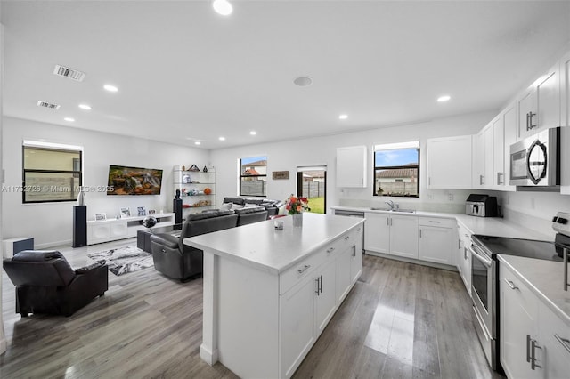 kitchen featuring a sink, visible vents, open floor plan, appliances with stainless steel finishes, and a center island