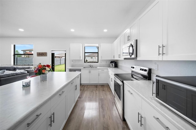 kitchen with stainless steel appliances, a wealth of natural light, a sink, and white cabinetry