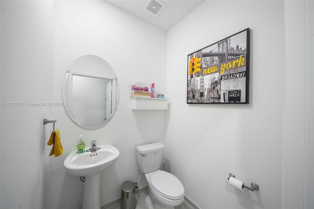 half bathroom with toilet, baseboards, and visible vents