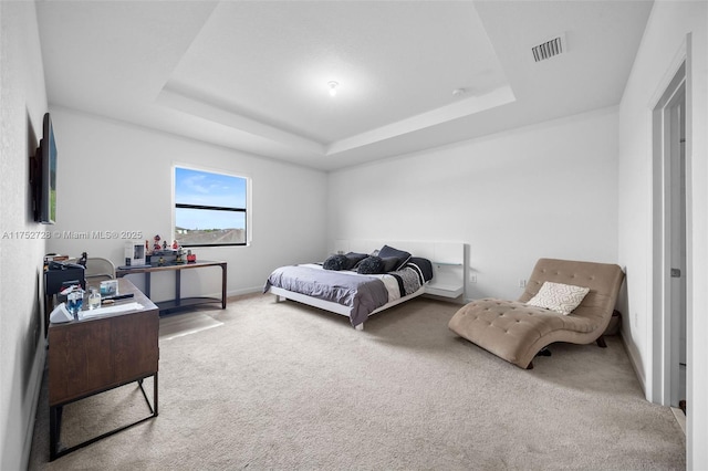 bedroom with visible vents, carpet, baseboards, and a tray ceiling