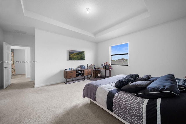 bedroom with carpet floors, a tray ceiling, and baseboards