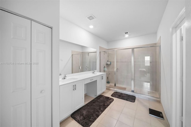 full bath with double vanity, visible vents, a sink, a shower stall, and a closet