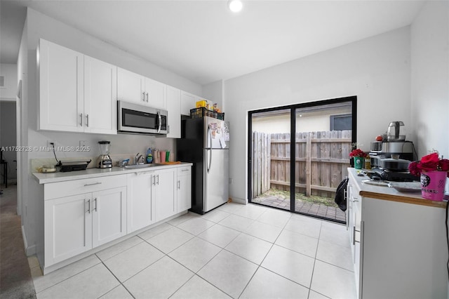 kitchen featuring stainless steel appliances, light countertops, white cabinetry, and light tile patterned floors