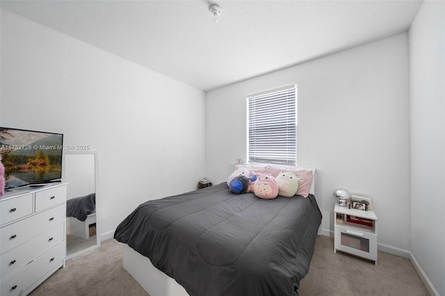 bedroom with light colored carpet and baseboards