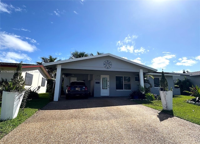 ranch-style house featuring driveway, a carport, and a front lawn