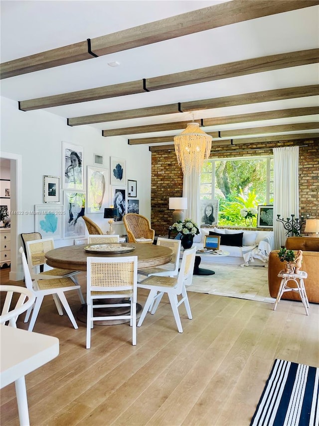 dining area featuring light wood-style flooring, a chandelier, and beam ceiling