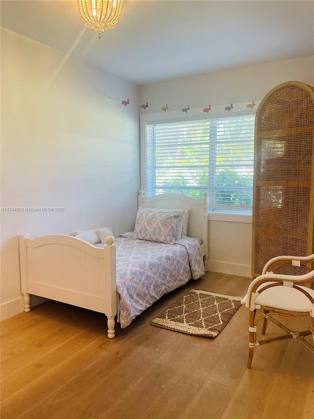 bedroom with multiple windows, baseboards, and wood finished floors