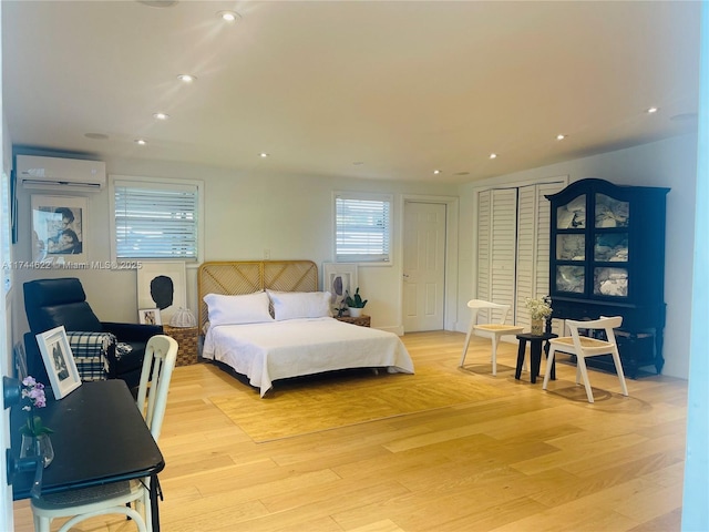 bedroom with light wood finished floors, a wall mounted air conditioner, and recessed lighting