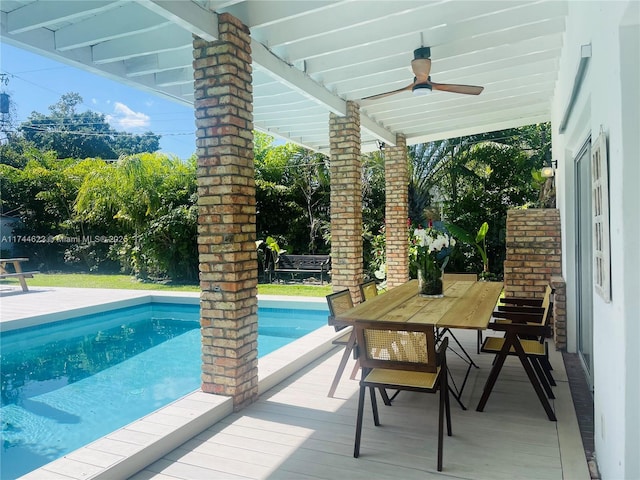 outdoor pool with a ceiling fan and outdoor dining space