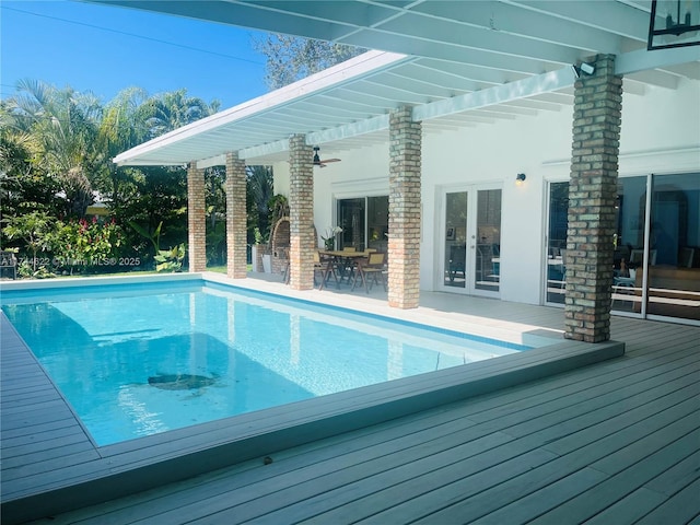 pool with ceiling fan, french doors, a wooden deck, and a pergola