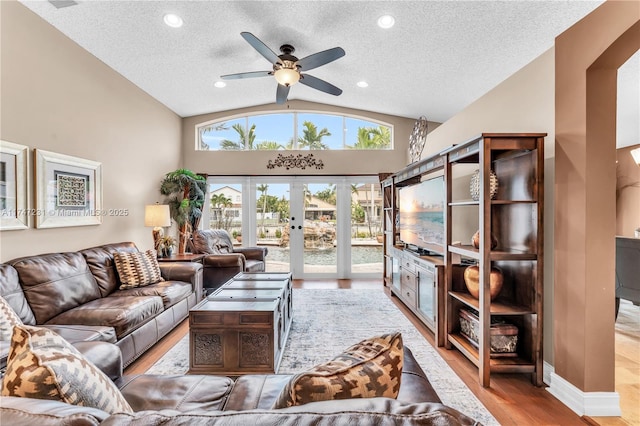 living room with lofted ceiling, a textured ceiling, baseboards, light wood-style floors, and french doors