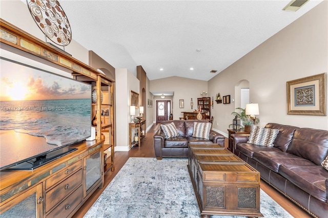 living area with vaulted ceiling, wood finished floors, visible vents, and baseboards